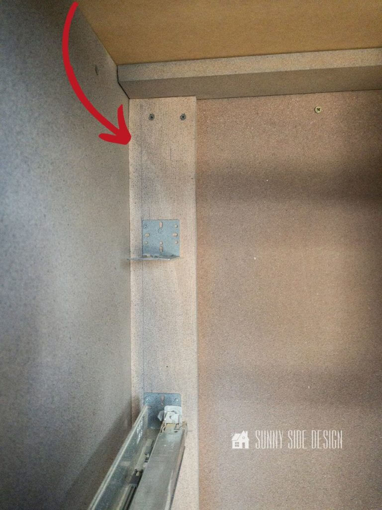 View of inside cabinet box, with red arrow pointing to mounting line for the brackets for the undermount drawer slides