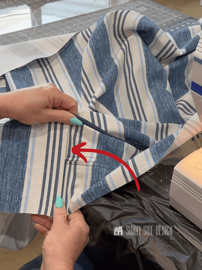 Woman's hands holding the box section of the cushion after the zipper section has been stitched in place. Blue and white striped fabric with a denim piping.