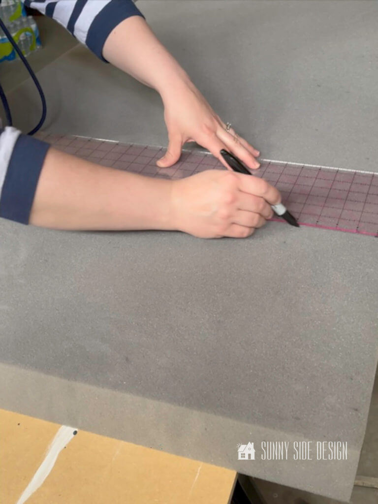 Woman marking the foam cushion with a sharpie marker.
