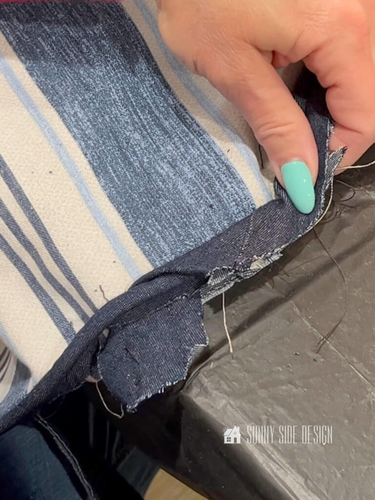 Woman's hand folding over the edge of the denim fabric to cover the edge of the piping when connecting the two ends together.
