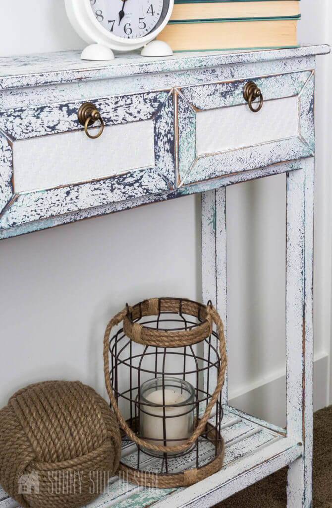 Painting furniture: salt wash finish on a console table for a worn and weathered look, white with navy blue and aqua variations. Decorated with books, clock, monkey fist ball and lantern.