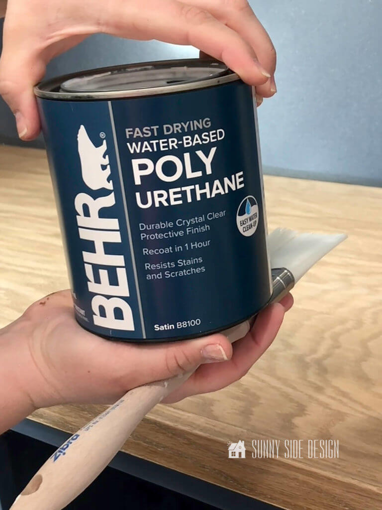 Woman's hand holding a can of water based polyurethane top coat.
