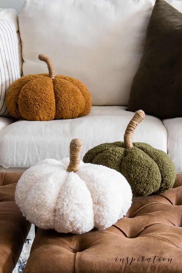 DIY Fall Decor ideas, soft and cozy pillow like pumpkins in rust, cream and green setting on a sofa, and ottoman.