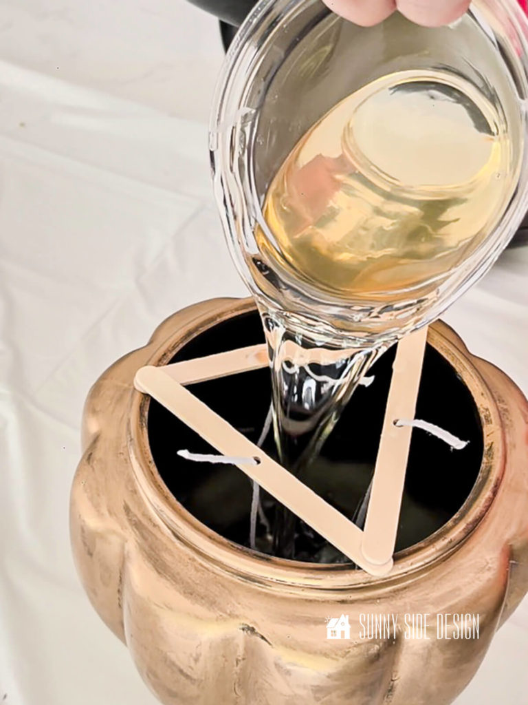 Wax is poured into the metallic gold pumpkin DIY for the Anthropology inspired metallic candle dupe.