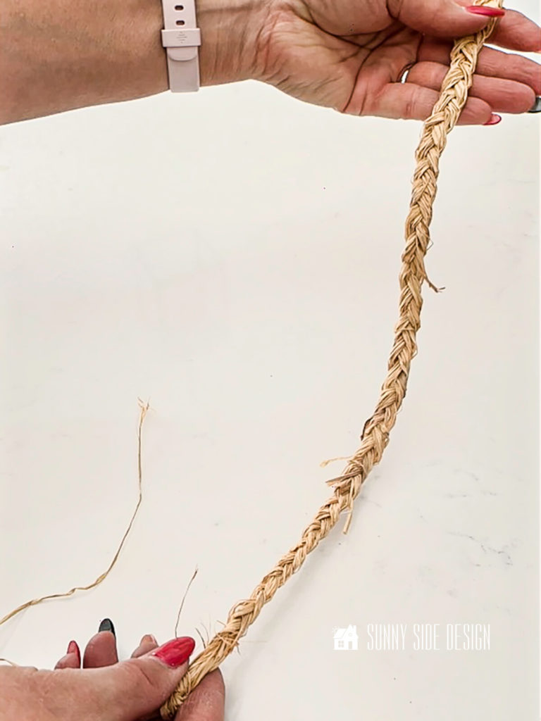 Woman's hand holding a long length of braided raffia.
