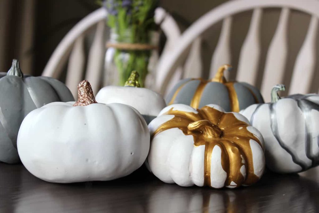 White and grey painted pumpkins with metallic gold and silver painted poured over the top of the pumpkins.