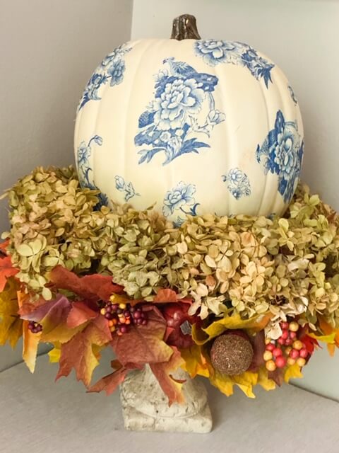 DIY Fall Decor ideas, decopaged chinoiserie pumpkin setting on a rustic iron vase with fall leaves and dried hydrangeas.