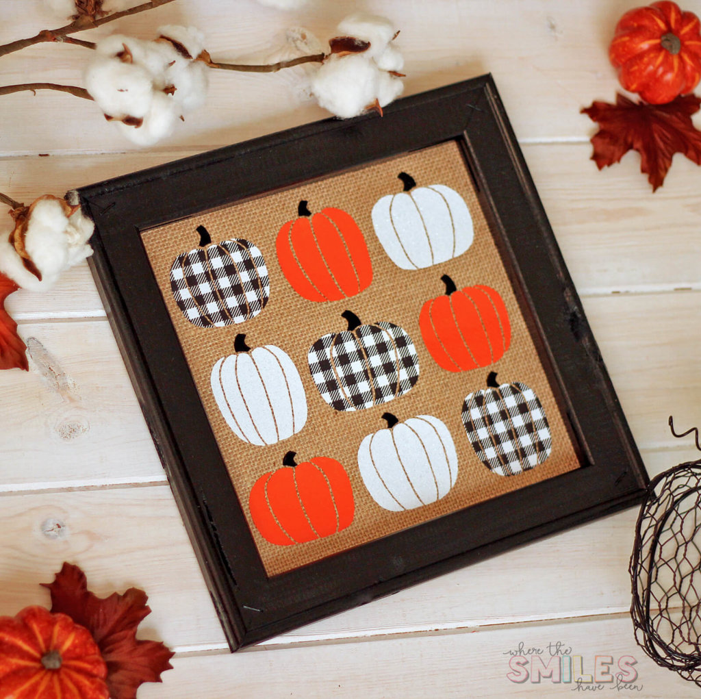 DIY wall art, burlap background with buffalo check, orange and white heat transfer vinyl pumpkins applied to the burlap in a 9 square grid in a black frame.