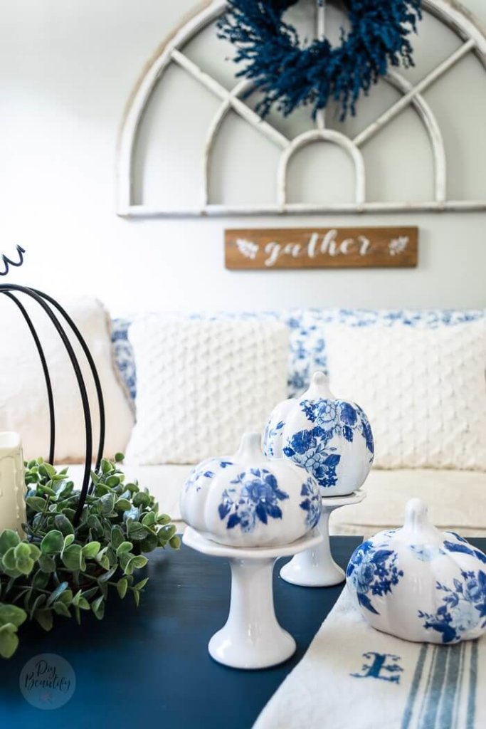 Pretty DIY blue and white chinoiserie pumpkins decopaged on white pumpkins, setting on candle stands, styled with iron pumpkin, greenery and candles.