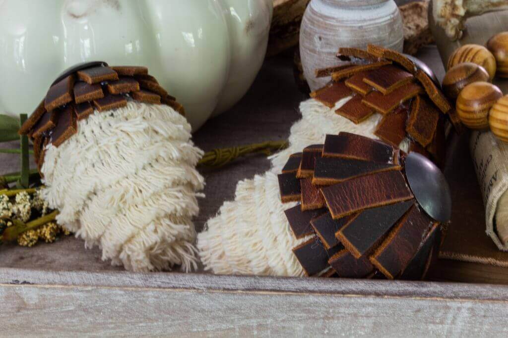 DIY Fall Decor ideas, DIY acorns made with white fringed trim, leather strips and an upholstery tack, styled in a galvanized tray with wood beads, book and a ceramic pumpkin.