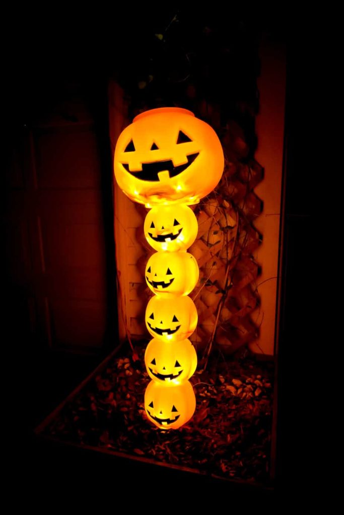 Easy Halloween decor ideas for your home. DIY orange Jack-o-lantern topiary lit up in the night sky.