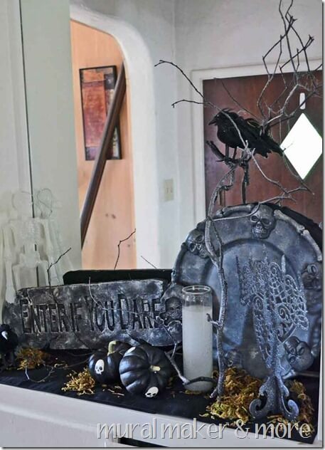 Mantle is decorated with cheap Dollar Tree decor, black skull place, black pumpkins, twigs, and a halloween sign.
