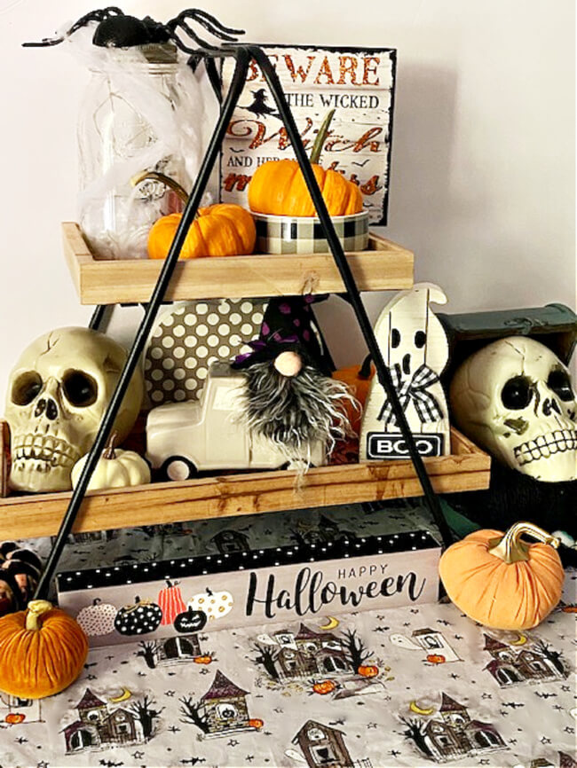 Wood and black iron tiered tray decorated with skulls, mini pupkins spiders, mini signs, gnome are easy Halloween decor ideas for your home.