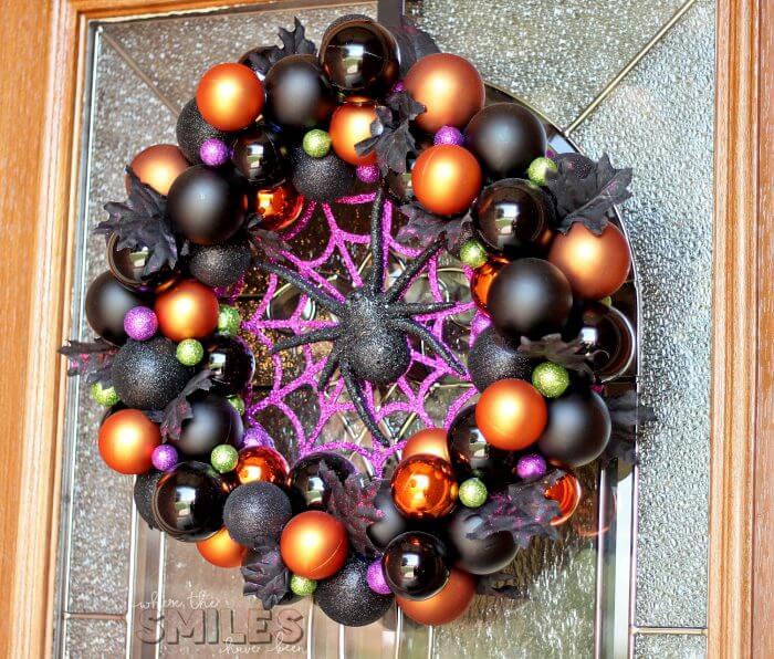 Easy Halloween decor ideas for your home. Black orange and purple ornament wreath with a purple glitter spider web and a black spider hanging on the front door.