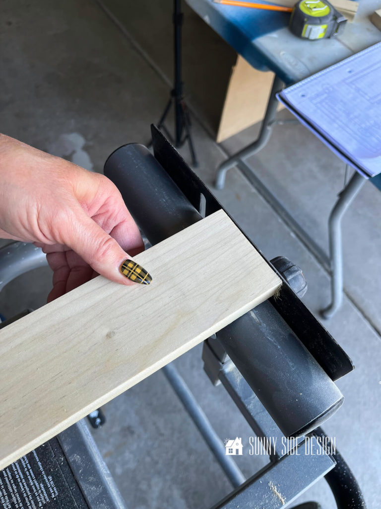 Woman places wood against stop at the miter saw.