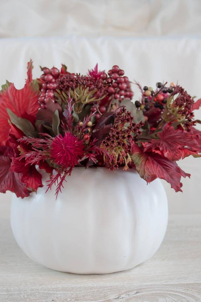 Fall centerpiece idea, white pumpkin filled with burgundy flowers, leaves and berries.