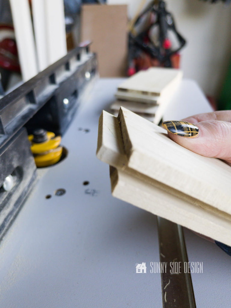 Woman's hand holding rabbet joint at router table for shaker doors.