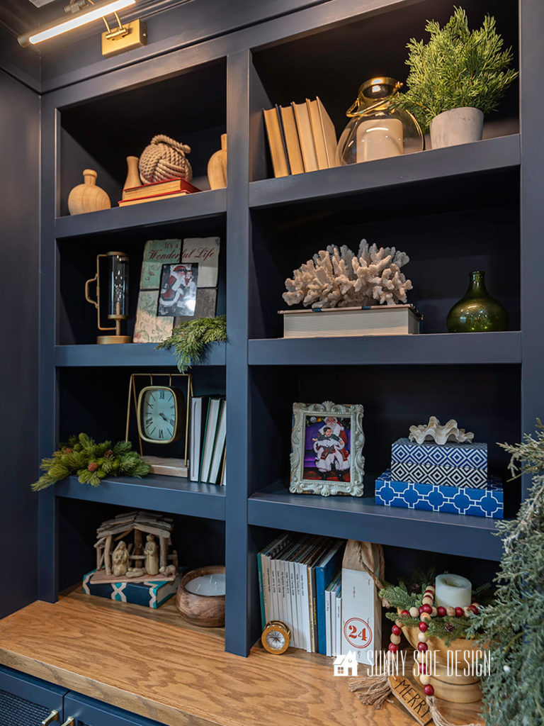 Navy blue built ins are embellished with realistic faux winter greenery, a small drift wood nativity, amd a red and white bead garland.