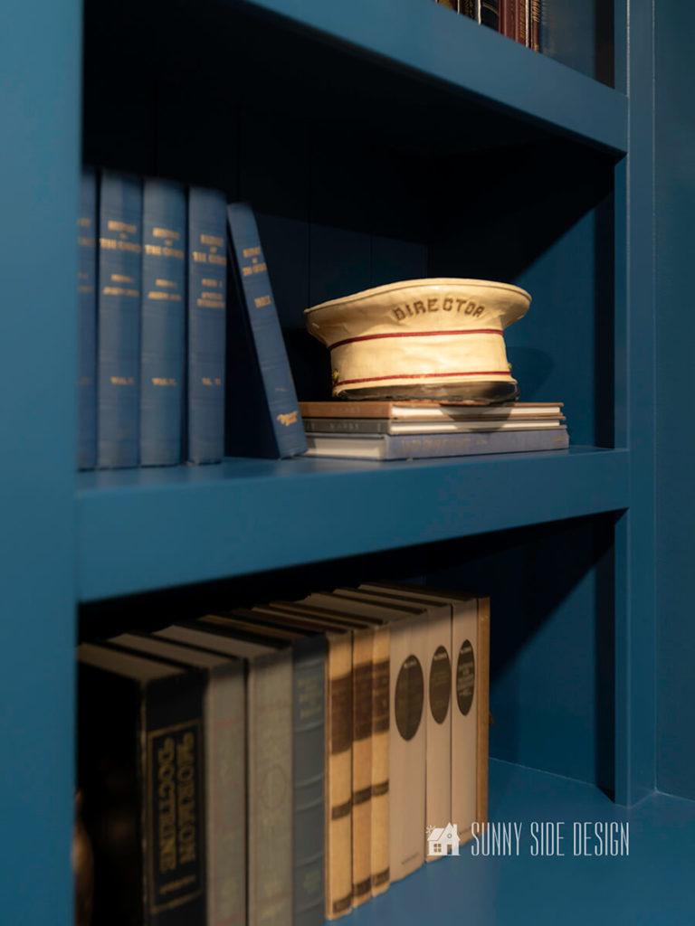 Built-in bookshelves with books, bronze bunny book ends, and a vintage band director hat.