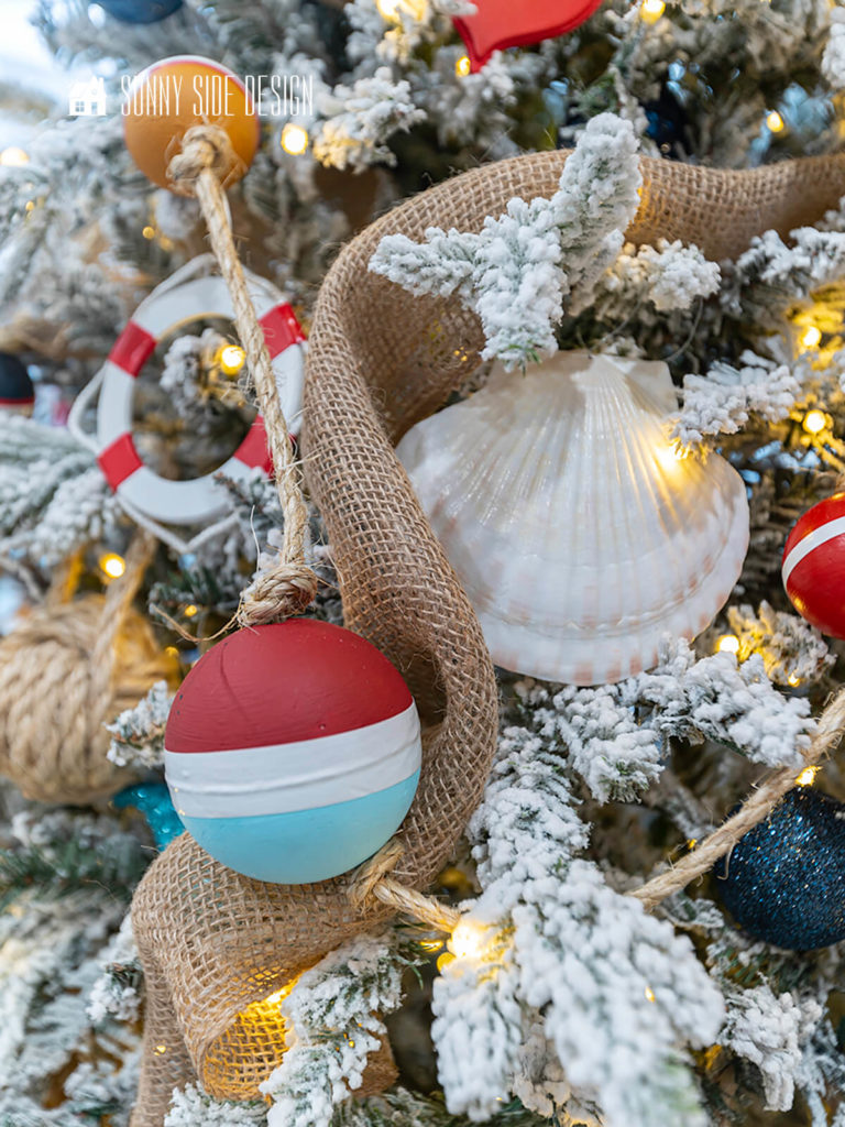 Close up view of the flocked Christmas tree with a buoy garland, life preserver ornament and seashells.