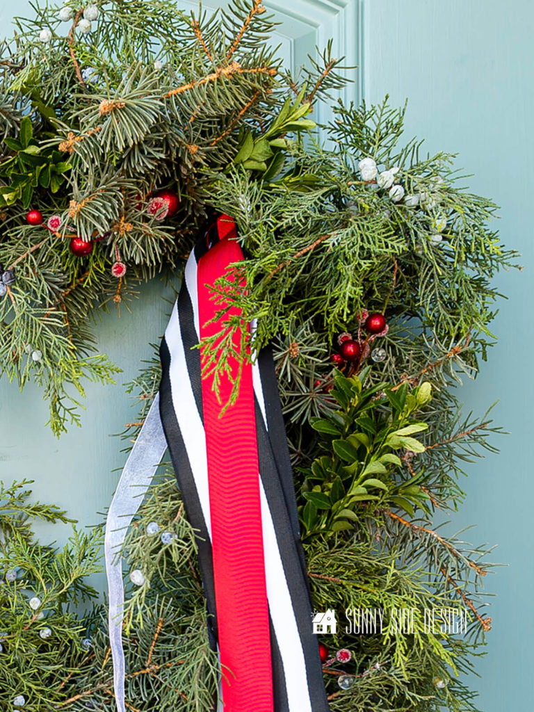Fresh Christmas wreath made with foraged evergreen stems, faux berries and ribbon streamers.