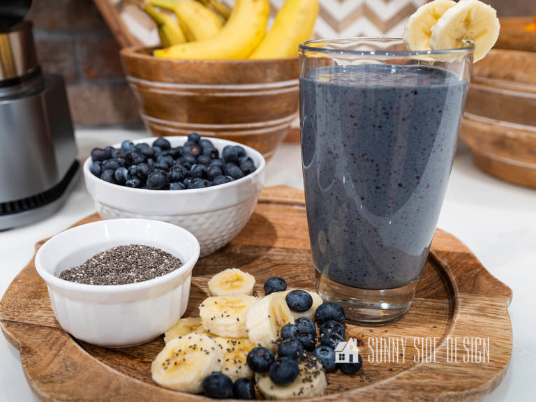 Healthy Blueberry Banana Smoothie on a wooden tray with fresh blueberries, bananas and chia seeds.