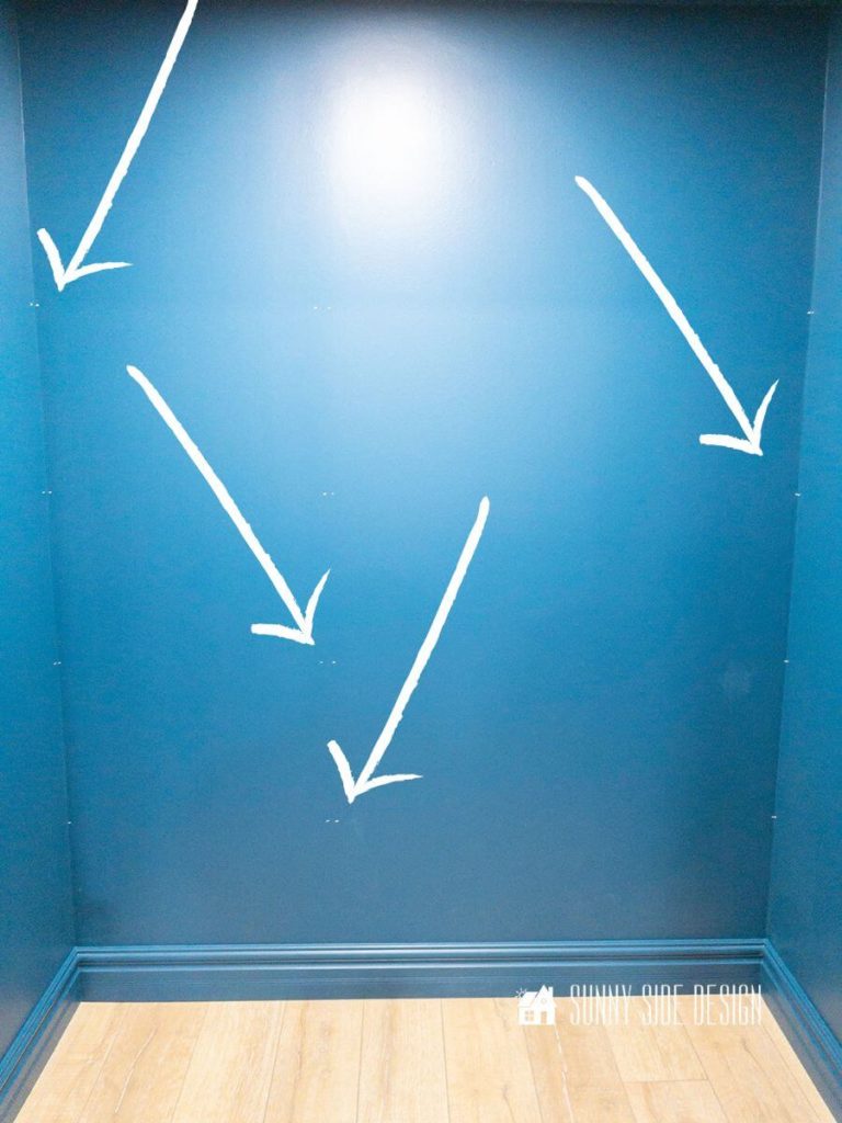 White arrows pointing out white chalk marks for the shelf placement in the closet.