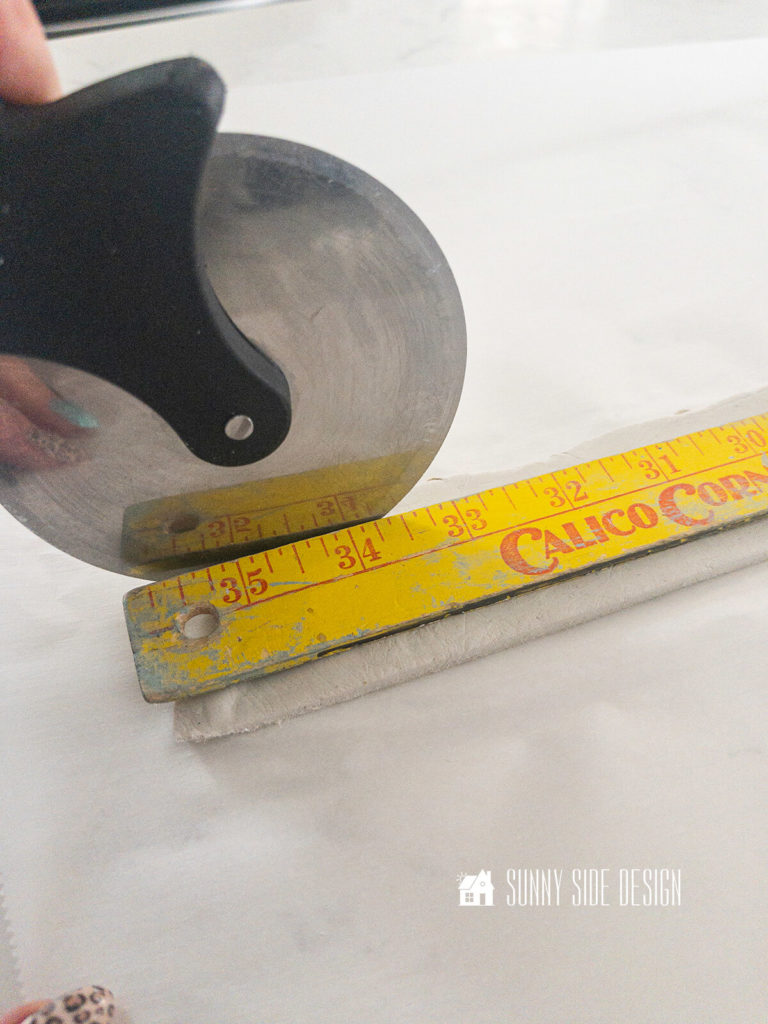 A pizza cutter is used to the the air dry clay into a strip for the lamp makeover.