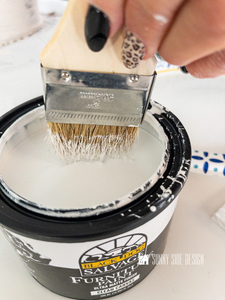 Chip brush is dipped into the can of white paint.