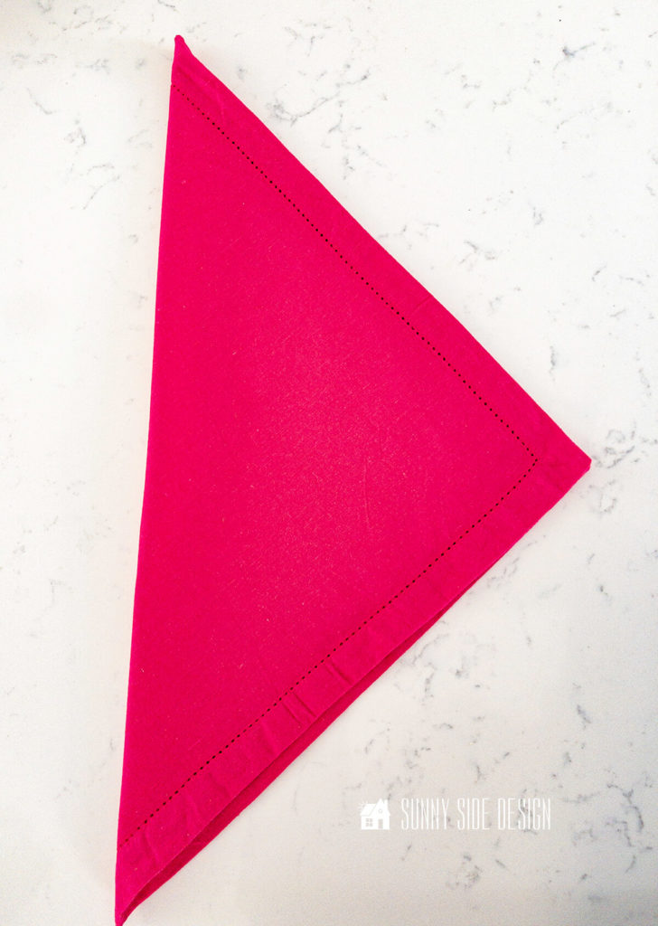 Hot pink napkin folded in half on diagonal.