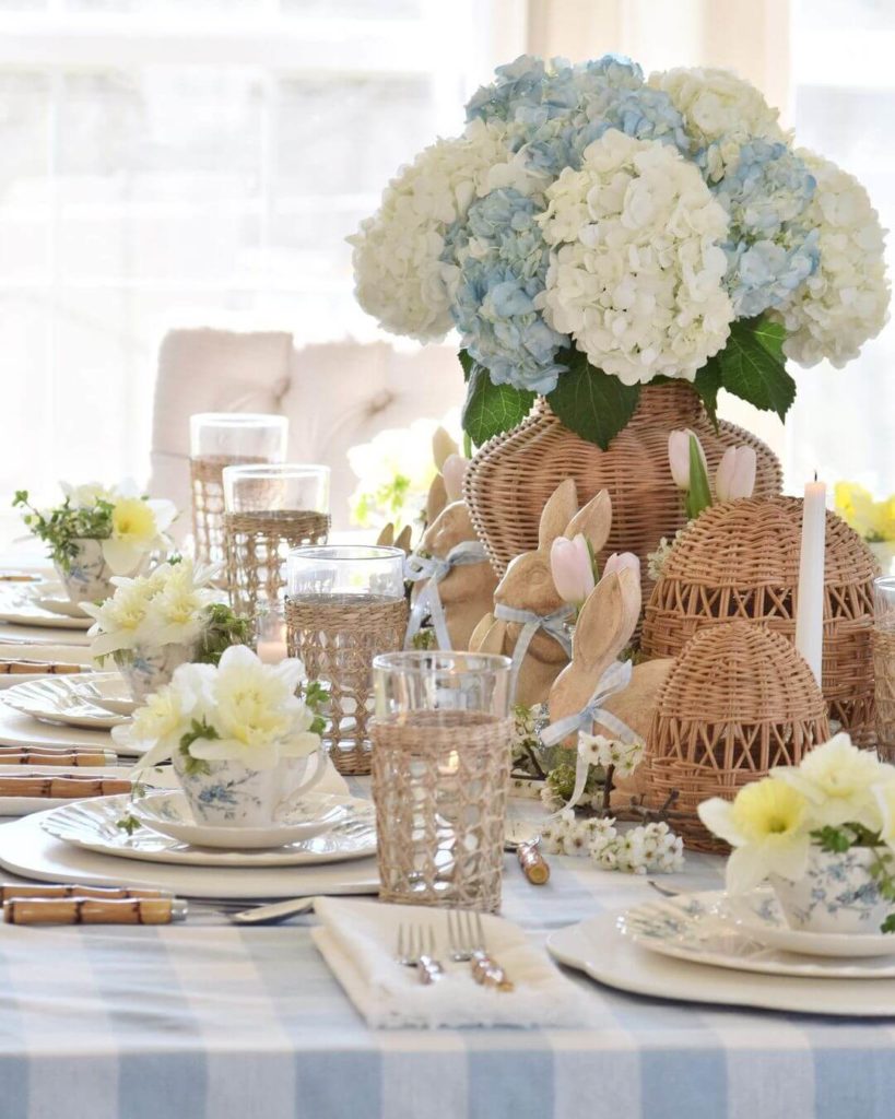 Pretty blue and white coastal themed Easter tablescape with fresh hydrangea in a woven vase.