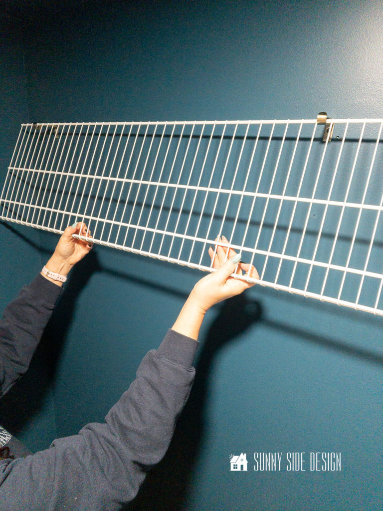 Hang a white wire shelf on hooks for artificial storage solution.