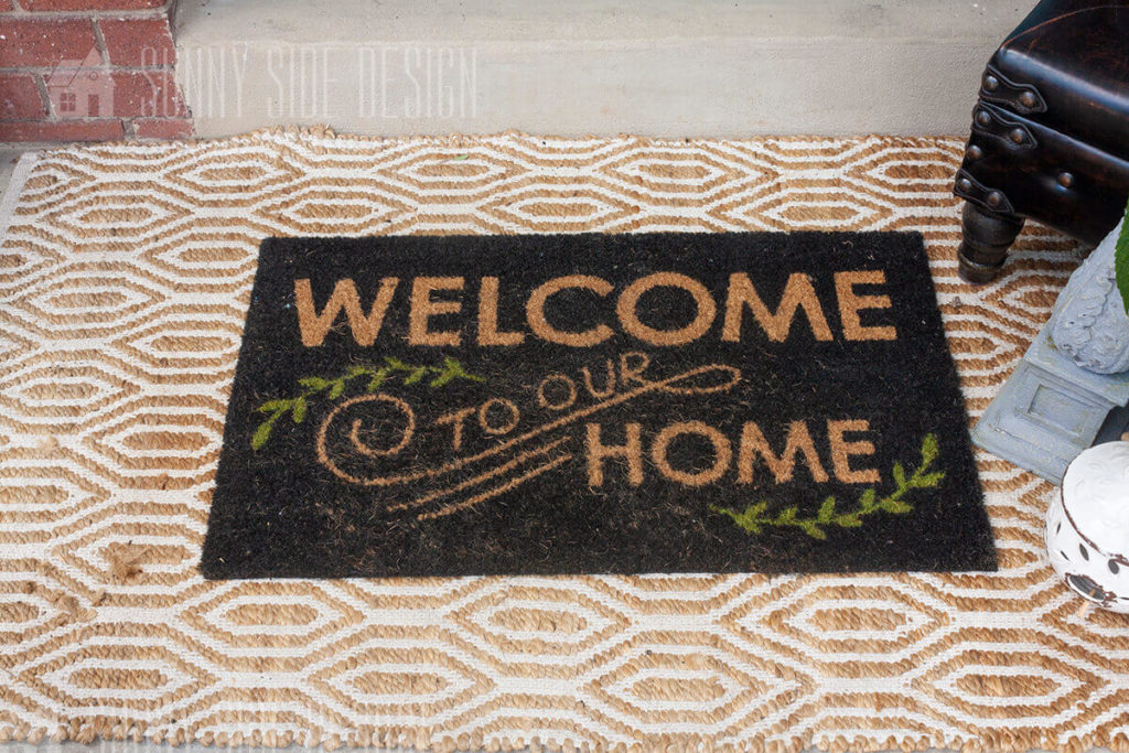 On a small front porch great visitors with a layered welcome mat.