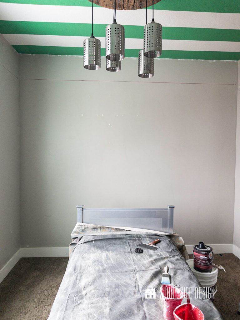 Room before painting, Green and white painted ceiling with grey walls and a rustic, industrial light fixture.