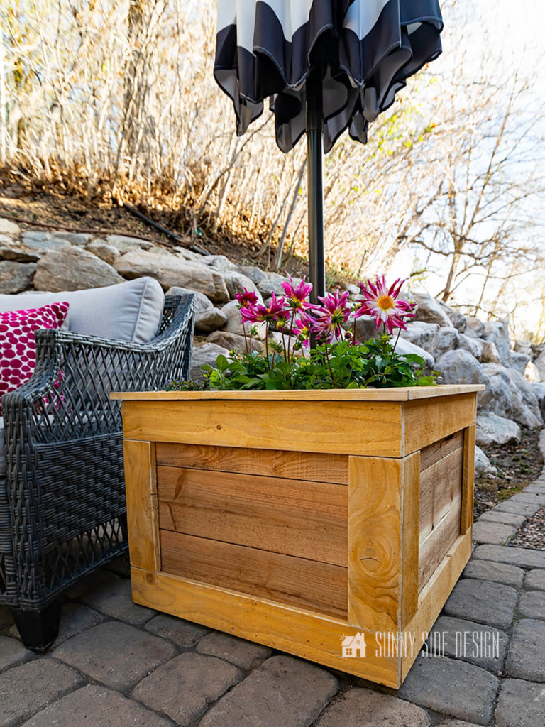 Mobile Cedar Planter Box with an umbrella stand on patio, planted with magenta dahlias, and herbs.