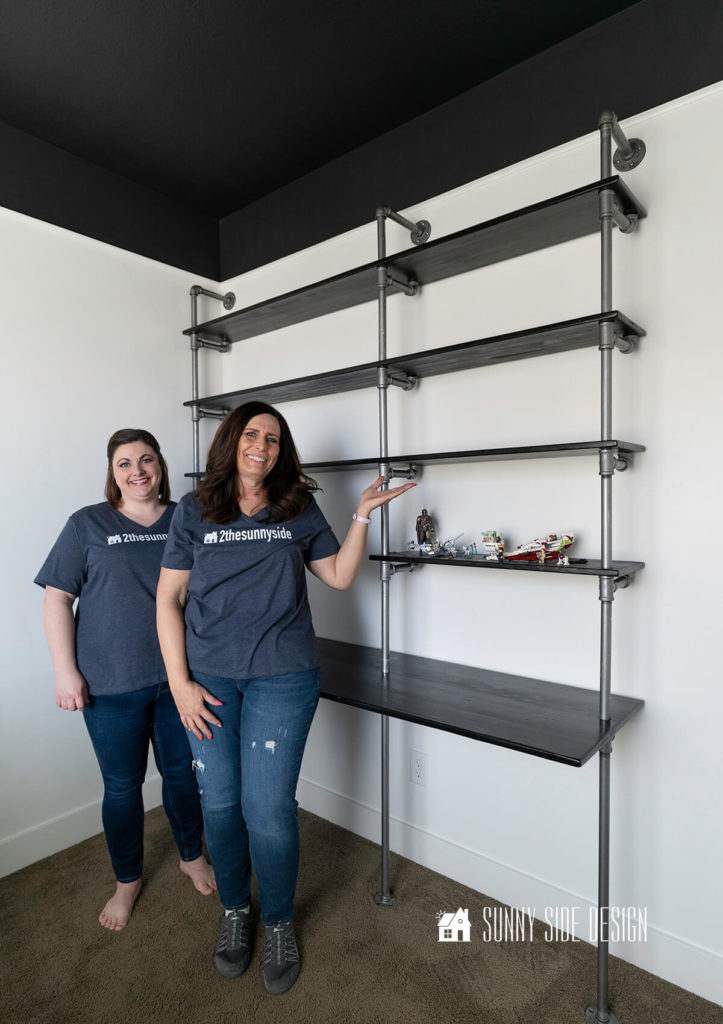 Women standing next to newly installed desk with wood and pipe, modernized with dark stain.