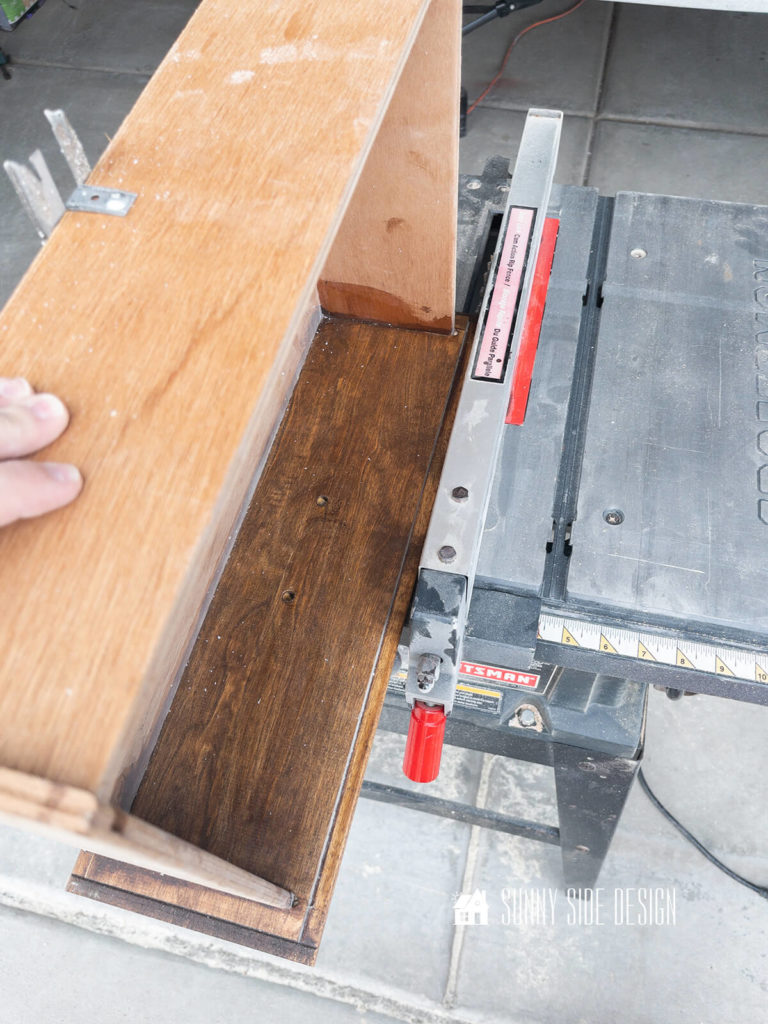Drawer front is placed on the table saw to cut off the routed edge for a more modern look.