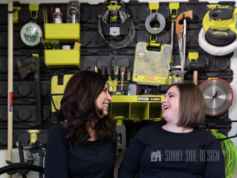 Two women smiling after installing the Ryobi Links garage wall storage. Wall storage holds power tools, screw drivers, saw blades, saws, power cords, batteries, extention poles, wire, tape, goggles, trimmer line, etc.