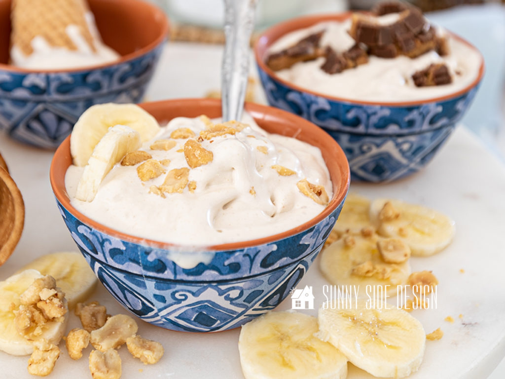 Peanut Butter Banana homemade ice cream topped with chopped nuts and sliced bananas in a blue and white bowl.