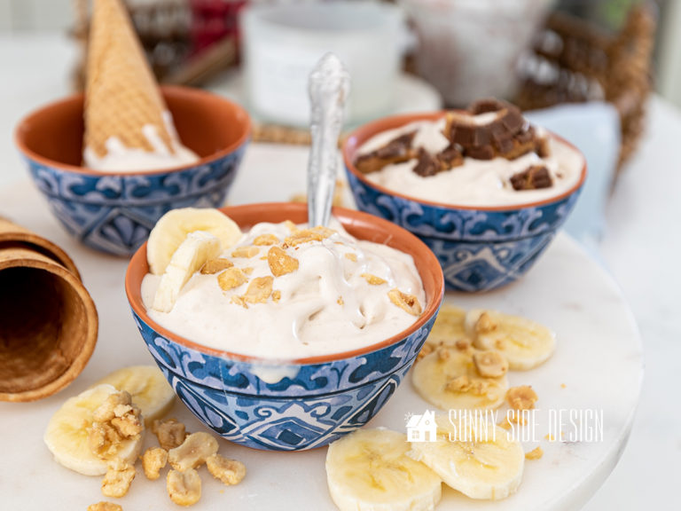 Peanut Butter Banana homemade ice cream topped with chopped nuts and sliced bananas in a blue and white bowl.