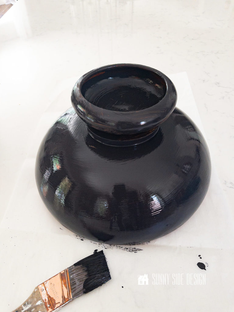 Black painted footed bowl upside down on a white countertop.
