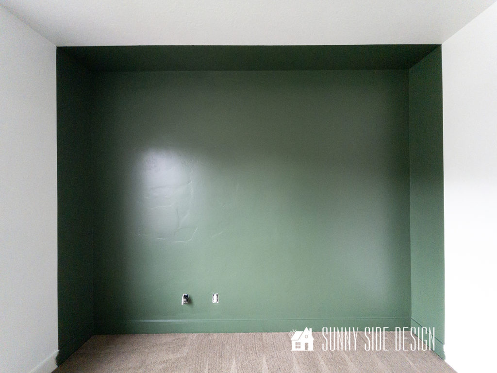 Painted forest green wall in a small bedroom.