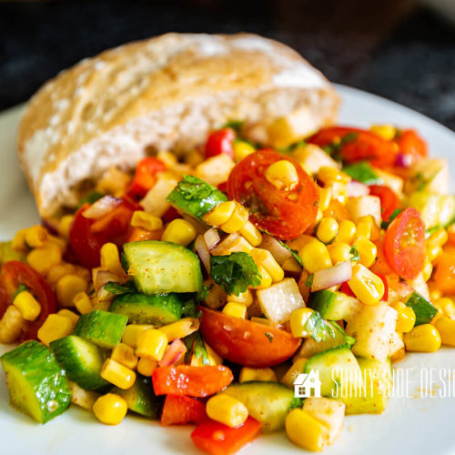 Easy corn salad recipe on a white plate with a roll.
