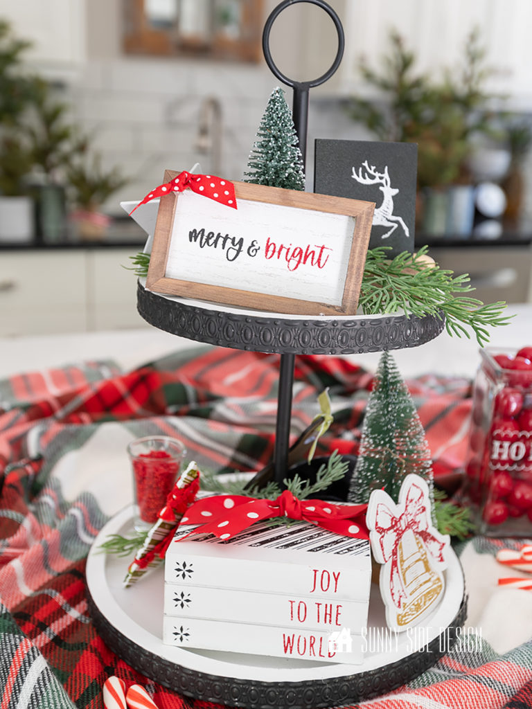 Christmas tiered tray decor, merry and bright sign, bottle brush tree, book stack with "joy to the world" tied with red polka dot ribbon, bell, greenery