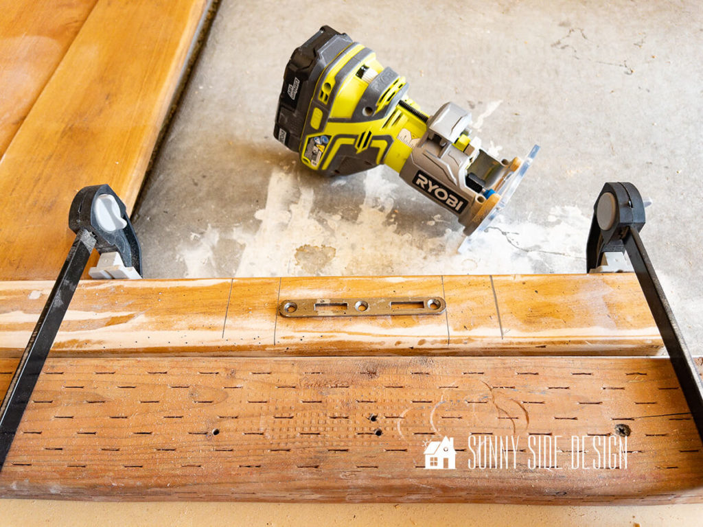 Two clamps hold the leg of the headboard to a jig to route a grove in the leg for the hardware.