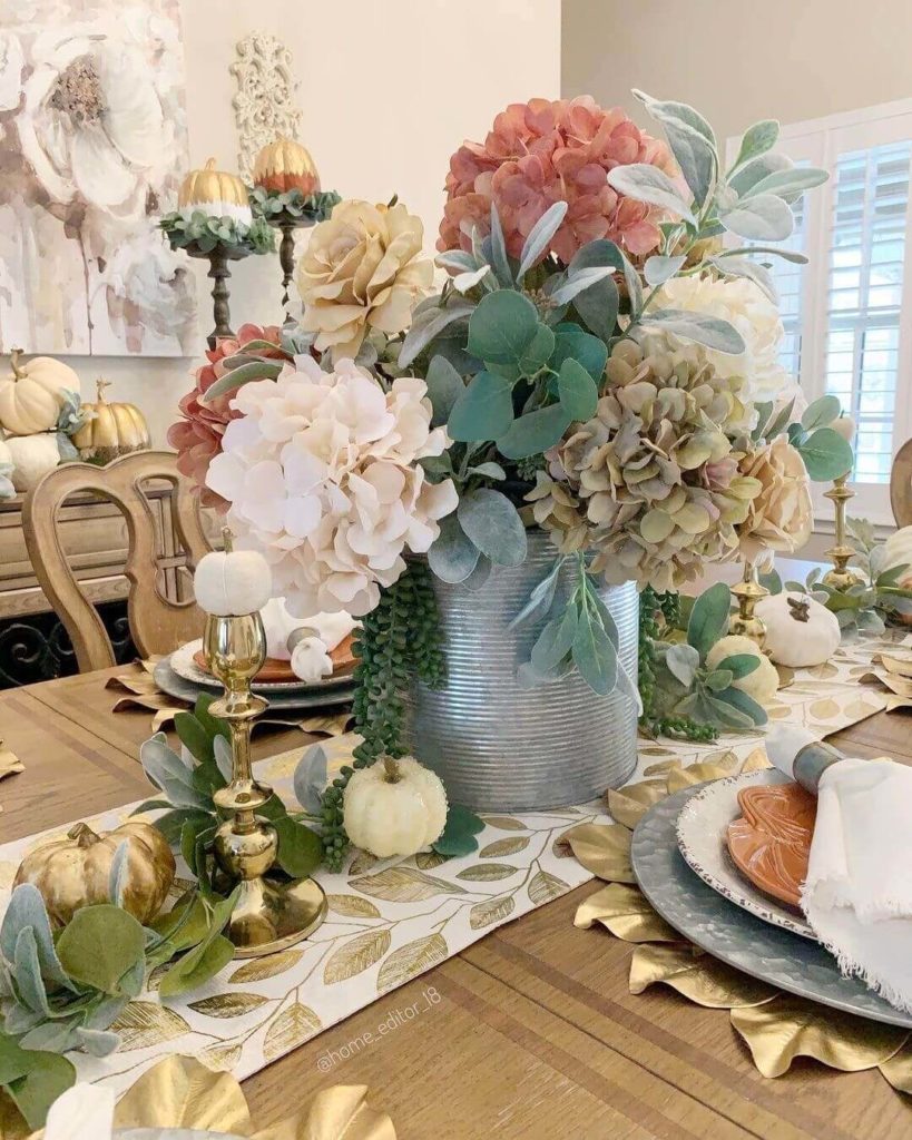 Pretty hydrangea, lambs ear, eucalyptus and baby tears in a galvanized vase form a pretty centerpiece on this Thanksgiving table decor.