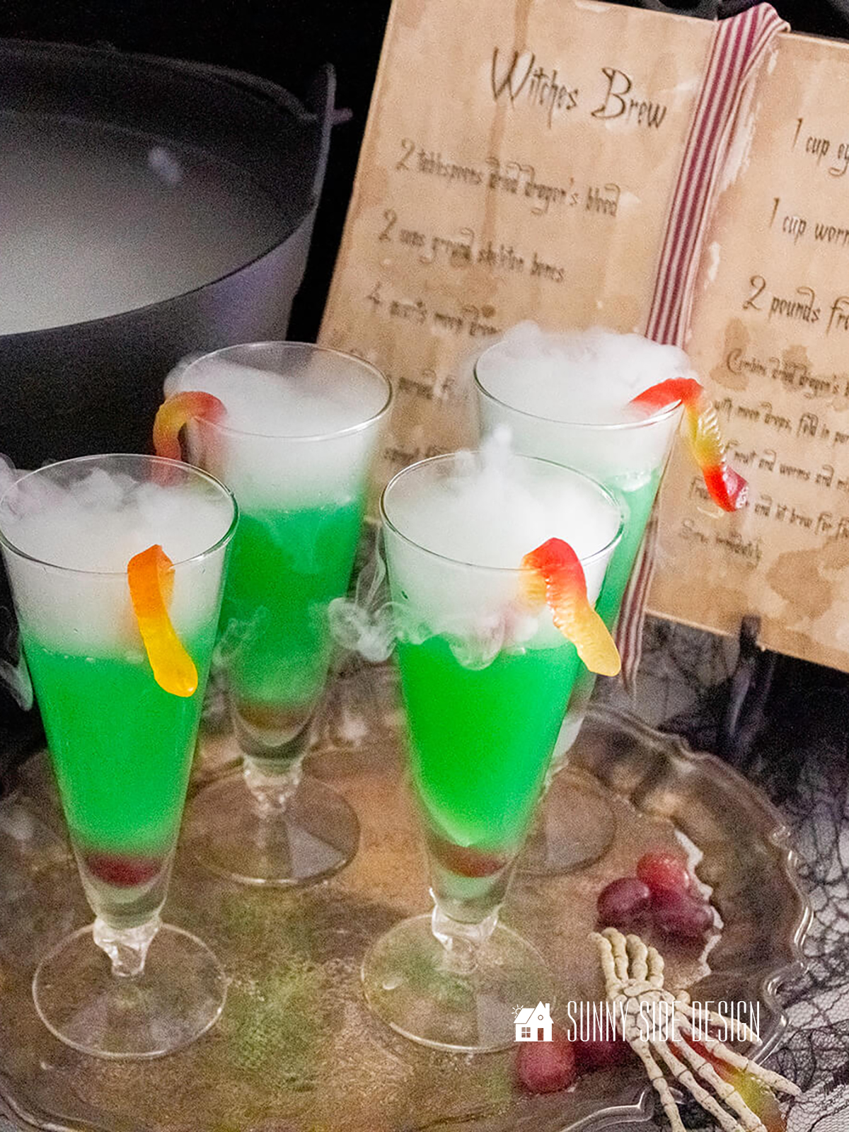 Wicked Witches Brew Recipe, smoking in a black cauldron, serves in goblets with gummy worms.
