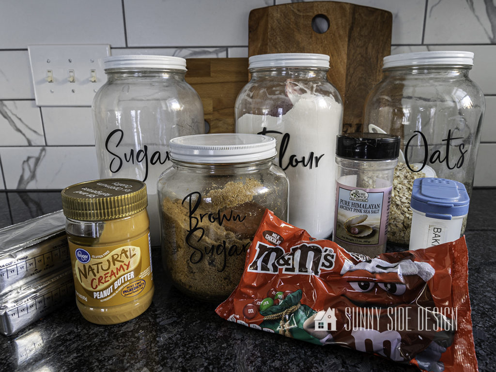 Ingredients for peanut butter oatmeal cookies with M&M candies, peanut butter, brown sugar, white sugar, flour, oats, salt, baking soda and M&M candies.
