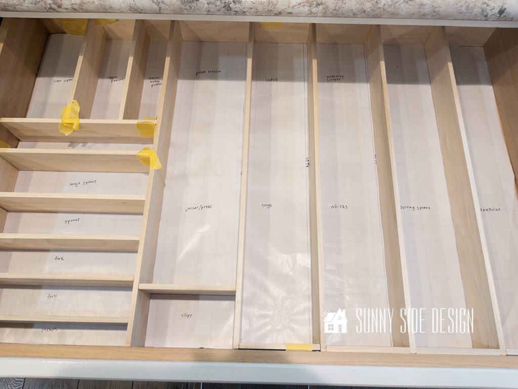 Custom wood DIY drawer dividers in drawer on paper plan, glued together.