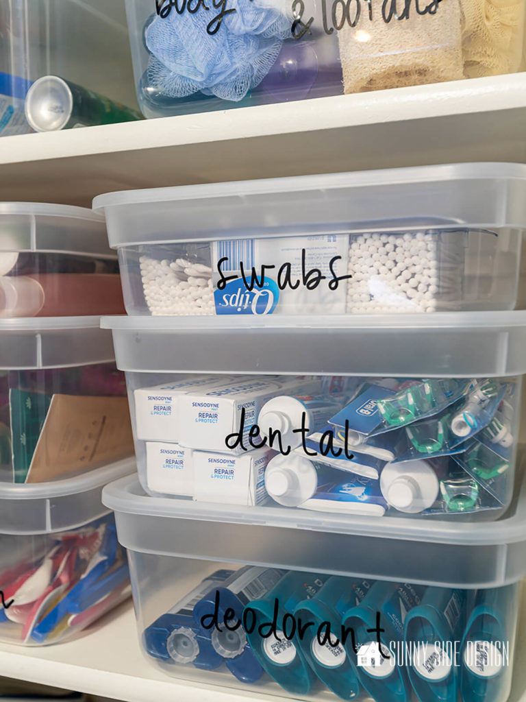 Keep. toiletries organized in a linen closet with labeled clear lidded containers.